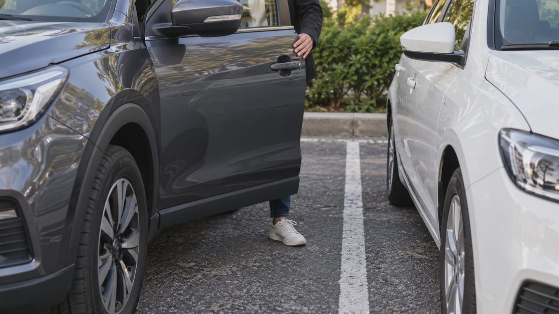 A person checking space to exit a parked crossover beside another vehicle.
